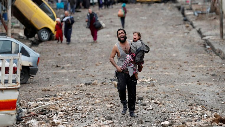Huilend draagt een man zijn dochter vanuit IS-gebied naar het door het leger bevrijdde gebied van Mosul. Beeld reuters