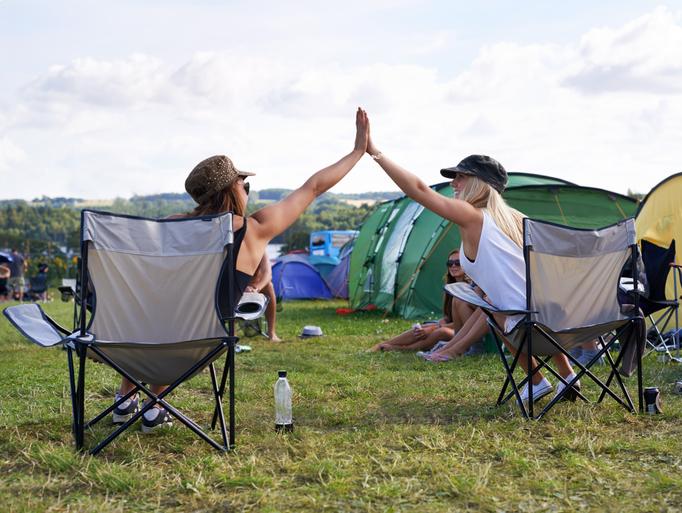 Twee vriendinnen geven elkaar high five op festival camping