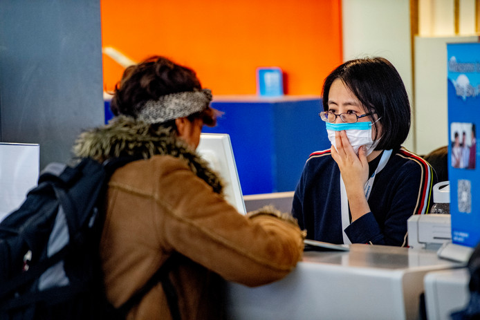 Personeel en reizigers op Schiphol met mondkapjes op ter bescherming van het coronavirus.