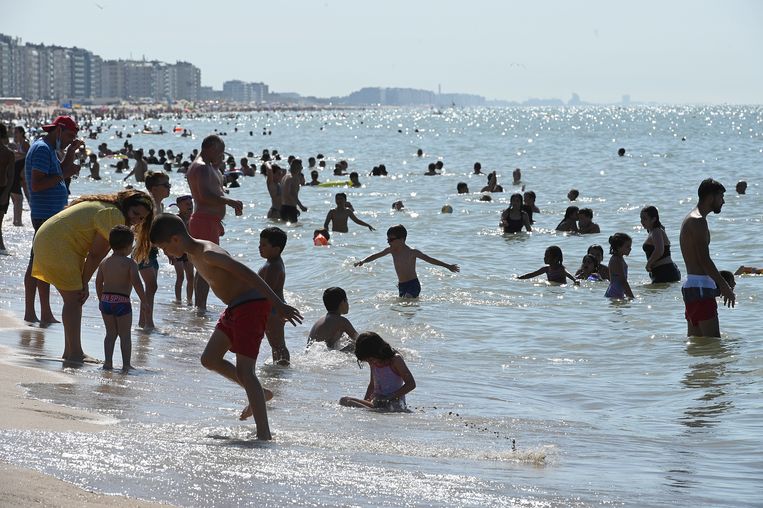 Spelende kinderen wagen zich in zee in Oostende. 