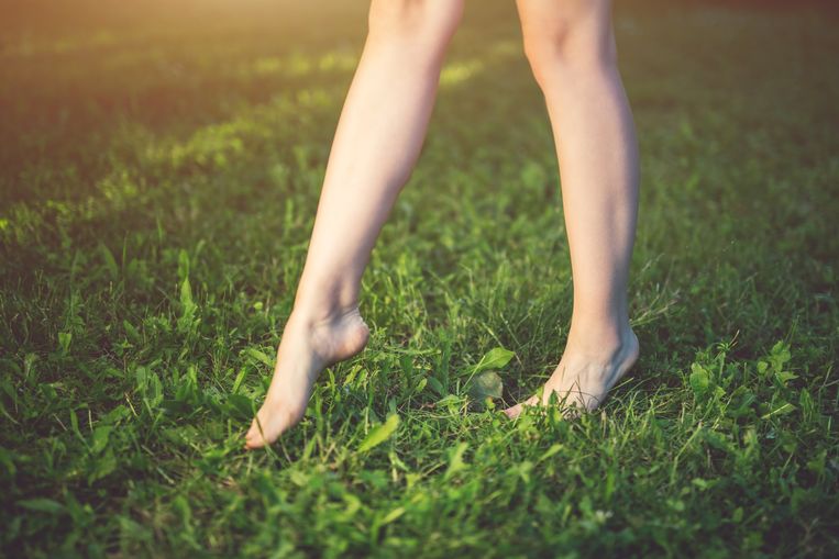 Voeten van jonge vrouw op groen gras.