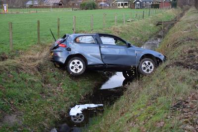 Auto raakt stoeprand, schiet over weg en komt in sloot tot stilstand